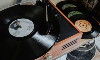 Gramofon odtwarza płytę winylową, a obok niego leżą kolejne płyty.
