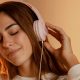 Młoda kobieta ma założone różowe słuchawki na uszach i słucha muzyki.