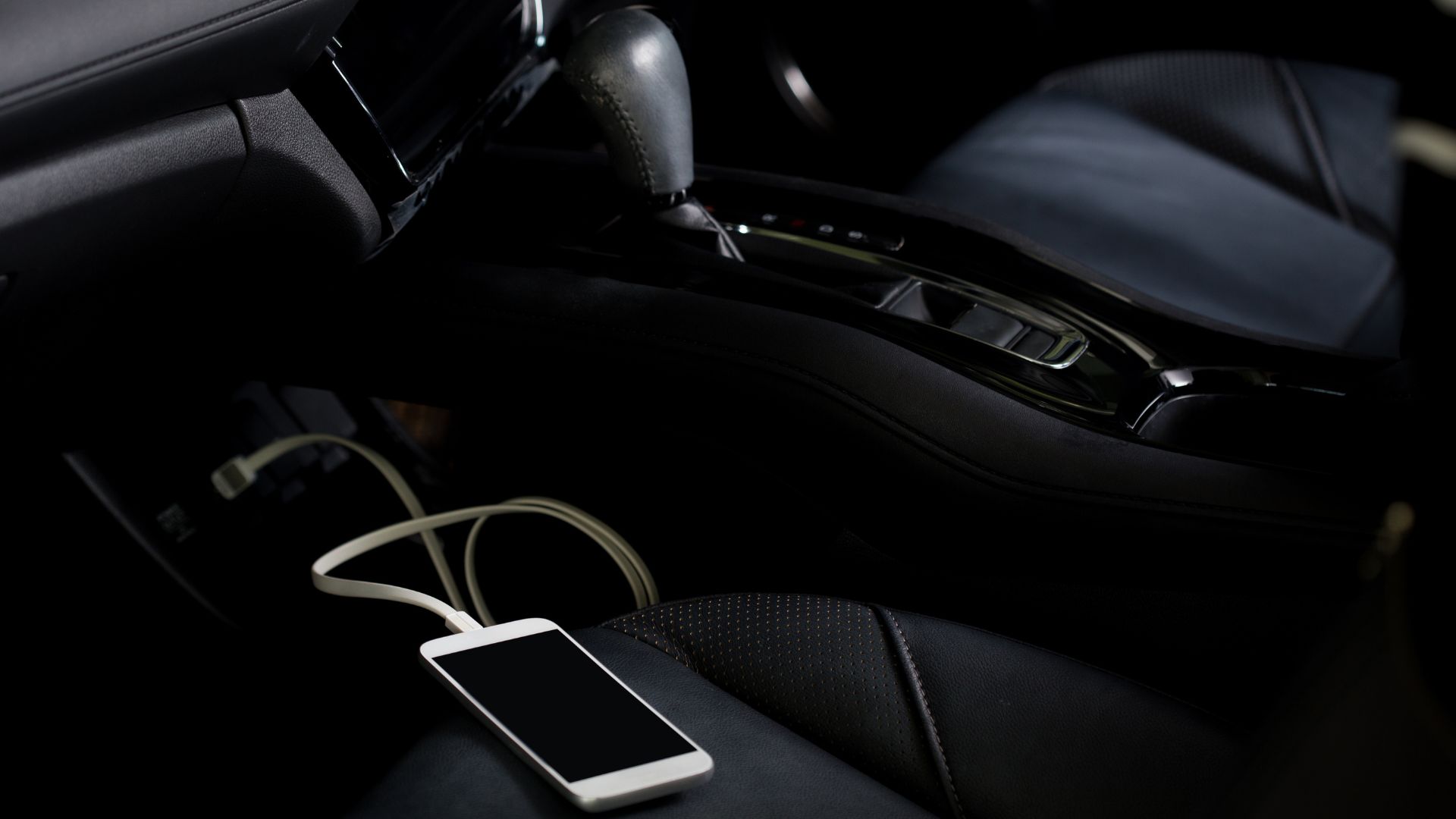 Ładowarka samochodowa do telefonu ładuje smartfon na siedzeniu kierowcy.
