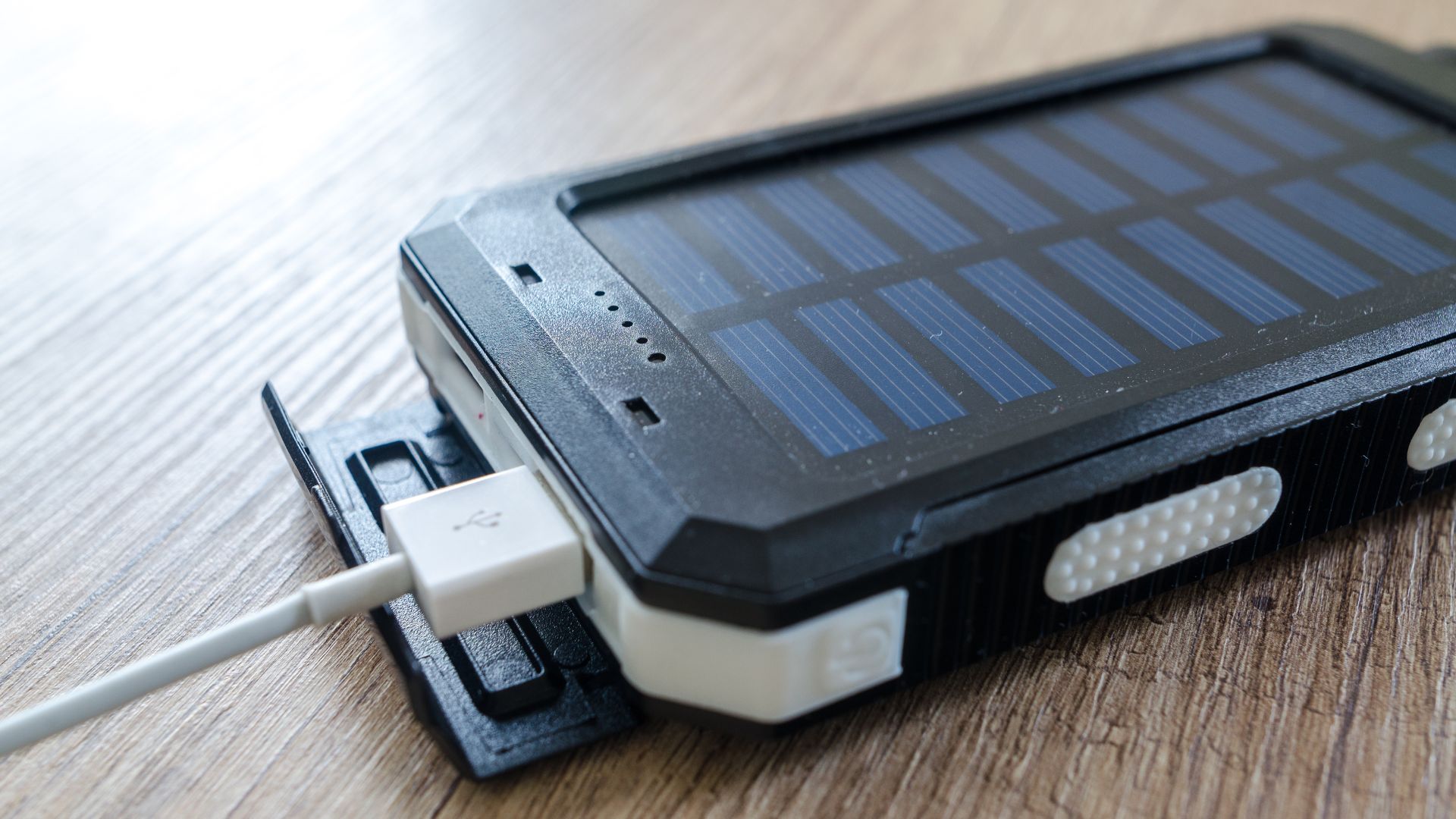Duży powerbank solarny z podłączonym kablem USB w kolorze białym.