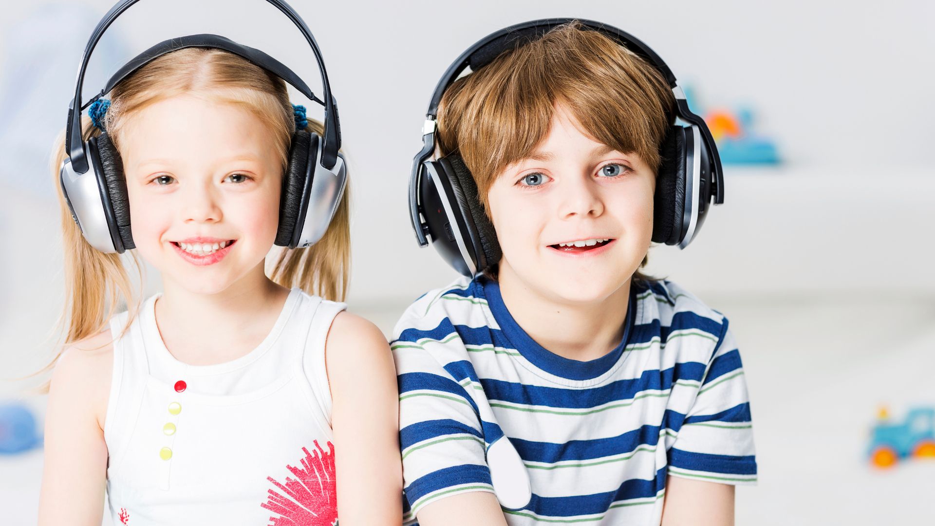 Chłopiec i dziewczyna mają założone nauszne słuchawki dla dzieci.
