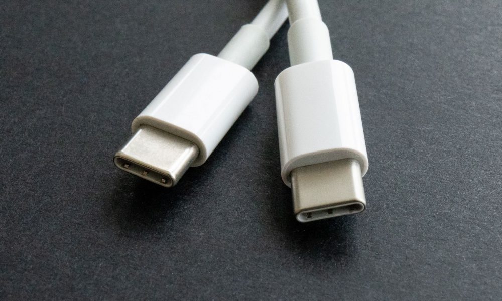 Dwa końce białego przewodu USB-C leżą na stole.