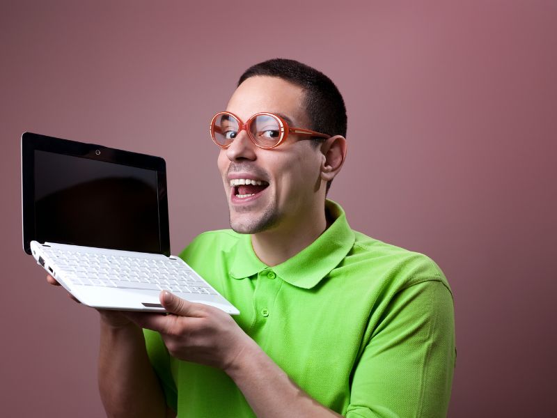 Na zdjęciu geek technologiczny z małym laptopem.